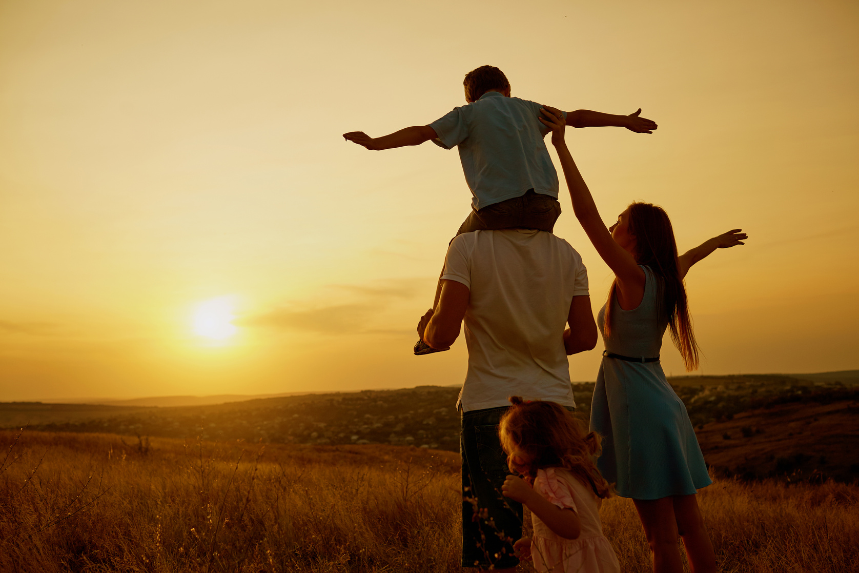 Happy Family in the Field at Sunset